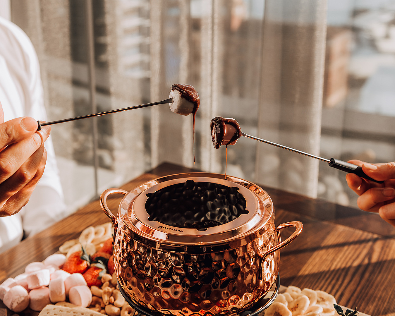 Two people dig into an epic chocolate fondue at Mövenpick hotel auckland, one of the best hotels in Auckland.