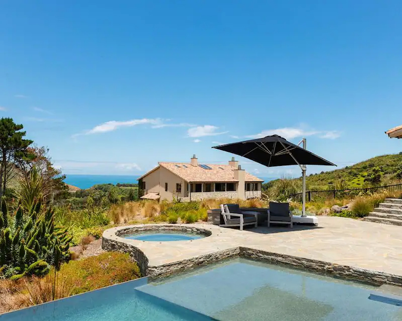 European-reminiscent stone pool and spa pool overlooking an estate in Muriwai.