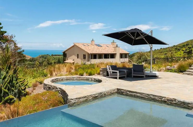European-reminiscent stone pool and spa pool overlooking an estate in Muriwai.