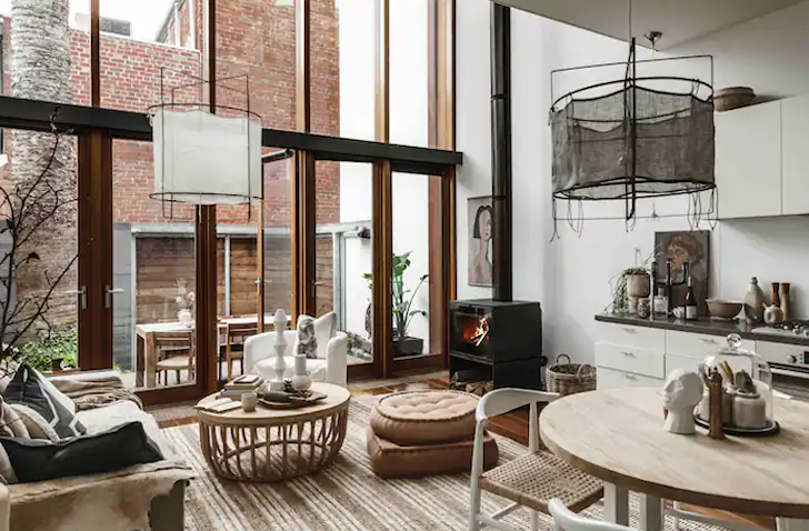 An Airbnb Melbourne living room with floor to ceiling windows, and a freestanding fireplace.