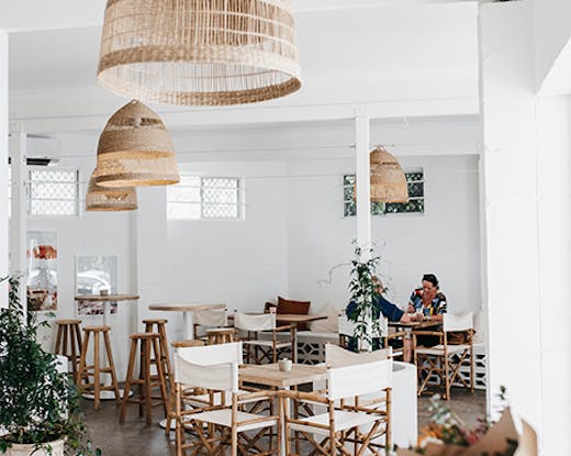 a beautiful white cafe interior with rattan hanging lamps