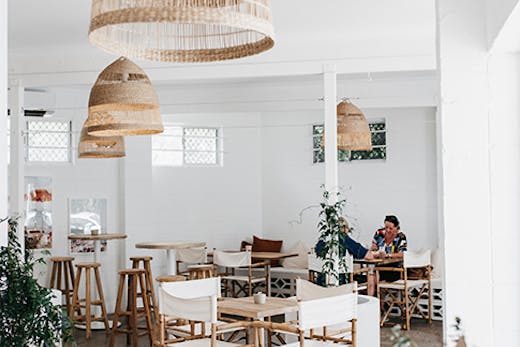 a beautiful white cafe interior with rattan hanging lamps