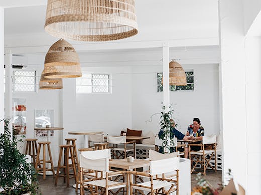 a beautiful white cafe interior with rattan hanging lamps