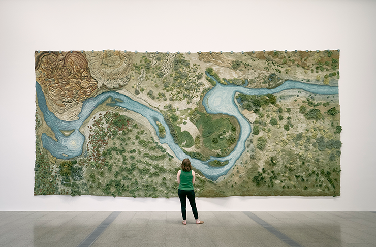 A person standing in front of a large artwork at an art gallery melbourne.