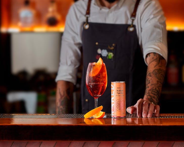 A man at a bar presenting Naked Life's Italian Spritz