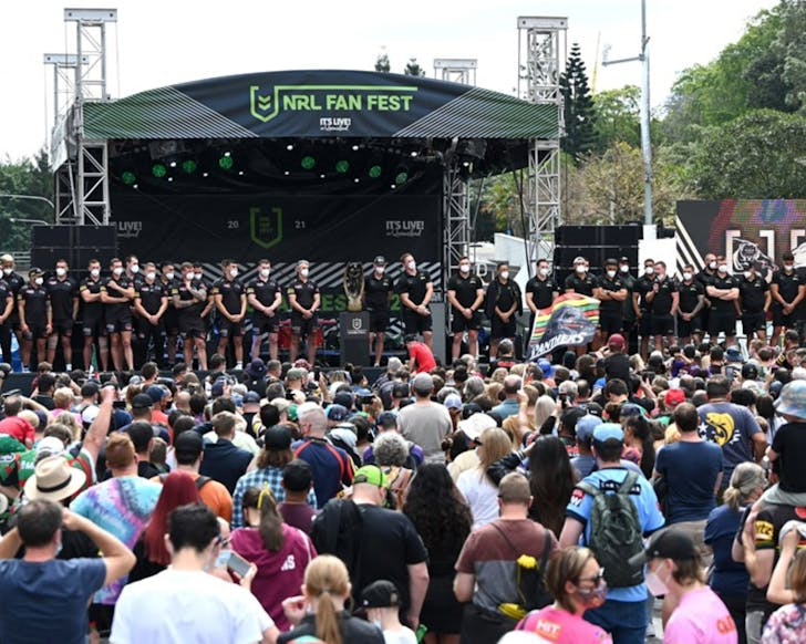 A wide shot of the NRL Fan Fest stage during the day with a large crowd standing in front of it.