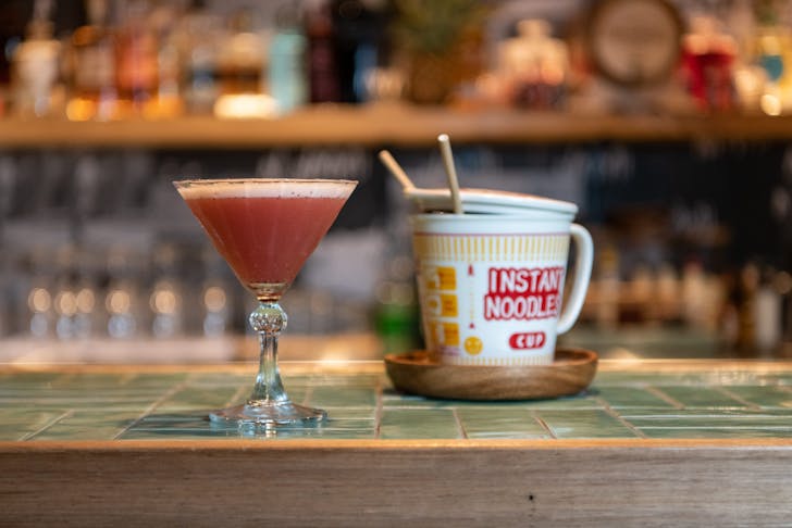 a cocktail and a cup of noodles