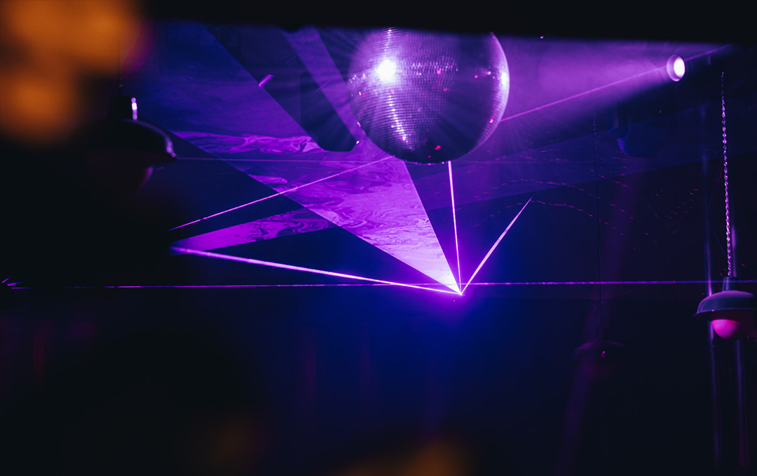 A dark dance-floor of one of the best nightclubs in Melbourne with a purple neon and disco ball
