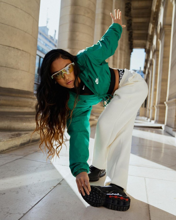 A woman wears a green top, white pants and sneakers from Nike one of the best activewear brands