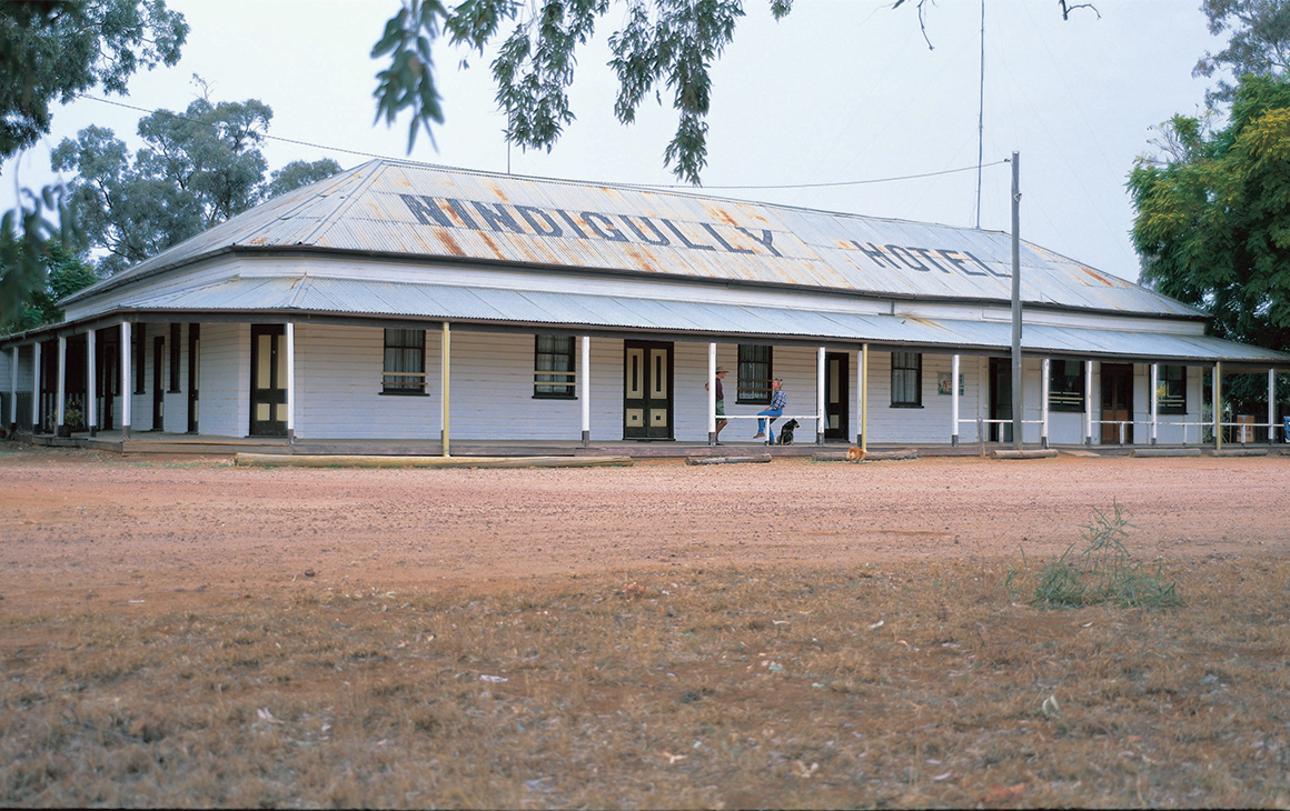 The exterior of Nindigully Pub, with a dirt yard and corrugated iron roof.