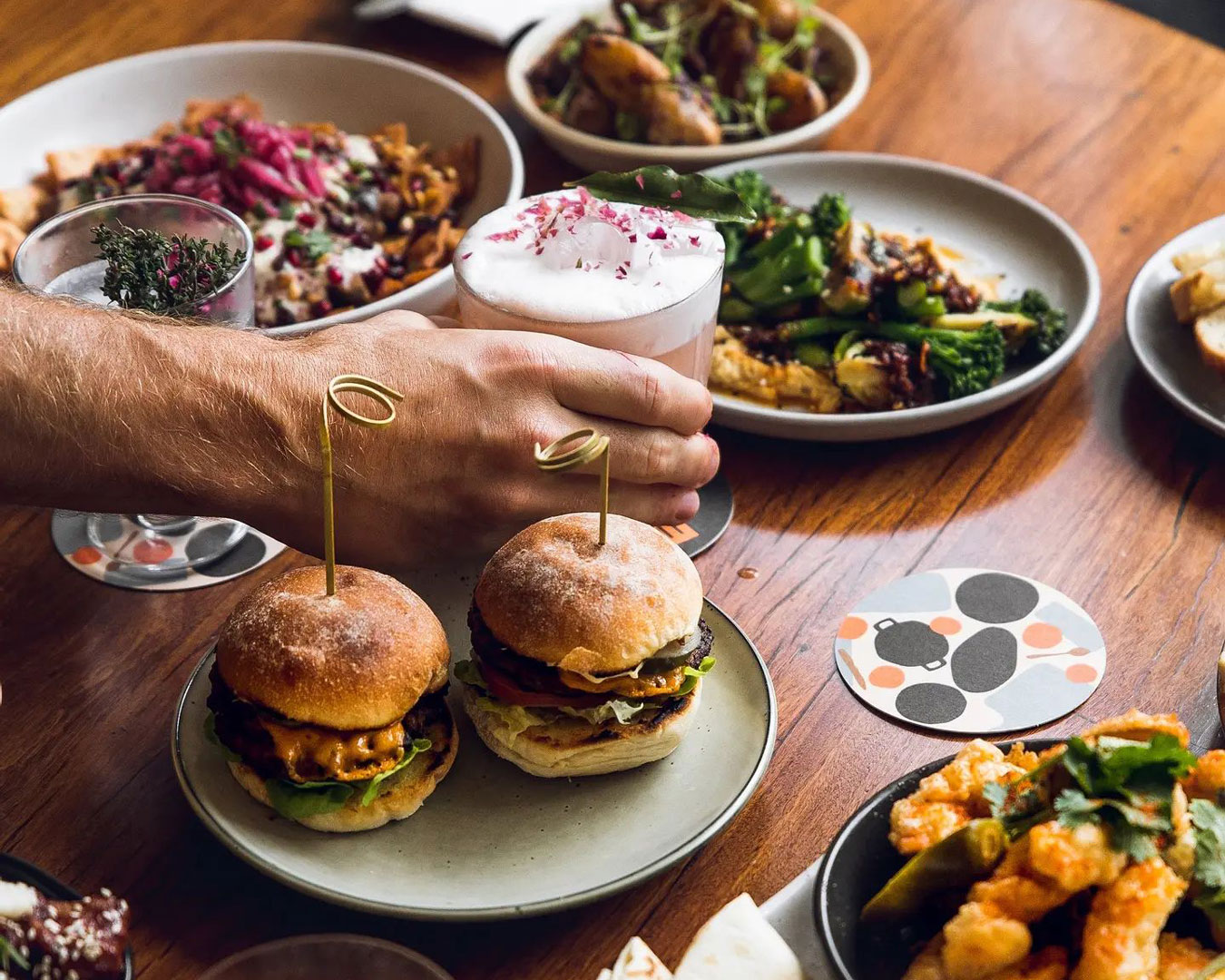 hand holding cocktail and table full of dishes