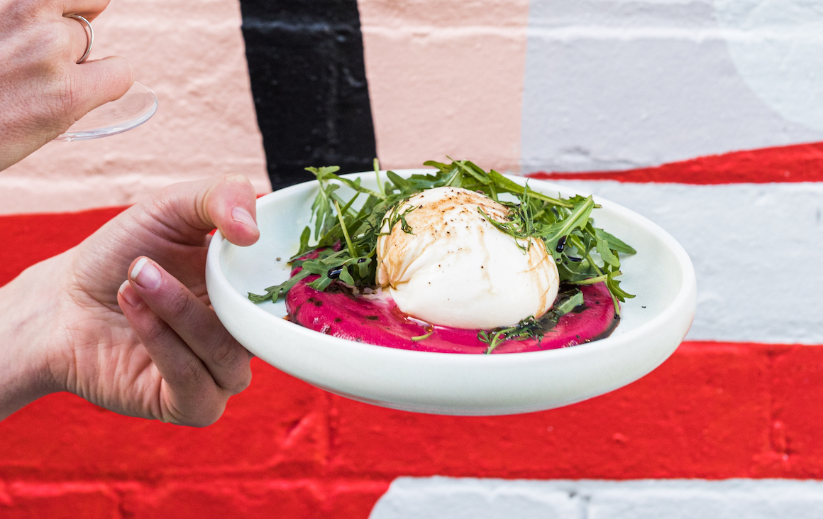 A plate of burrata on a bed of beetroot dip