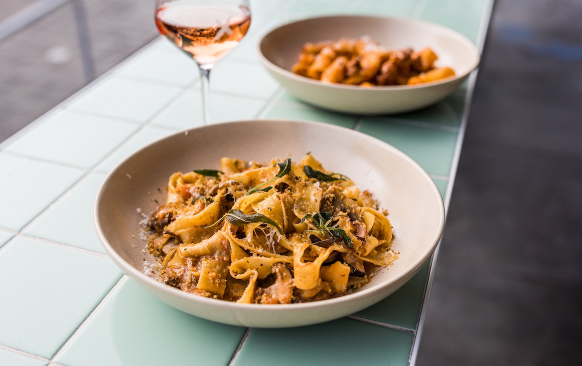Two bowls of pasta sit on a benchtop