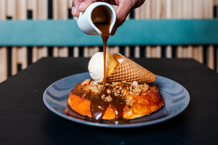 syrup being poured on banana pancakes from Nogi Lane