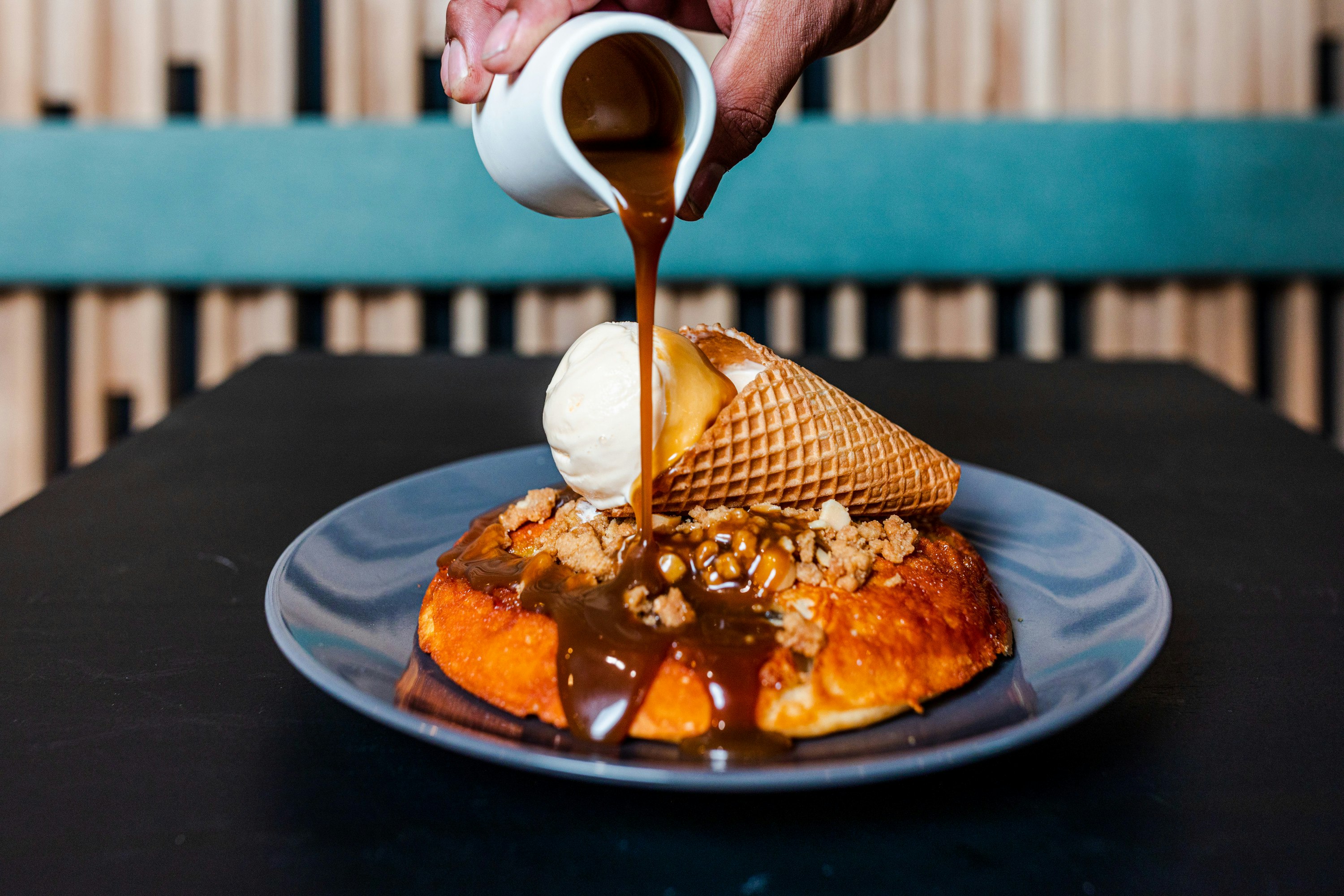syrup being poured on banana pancakes from Nogi Lane