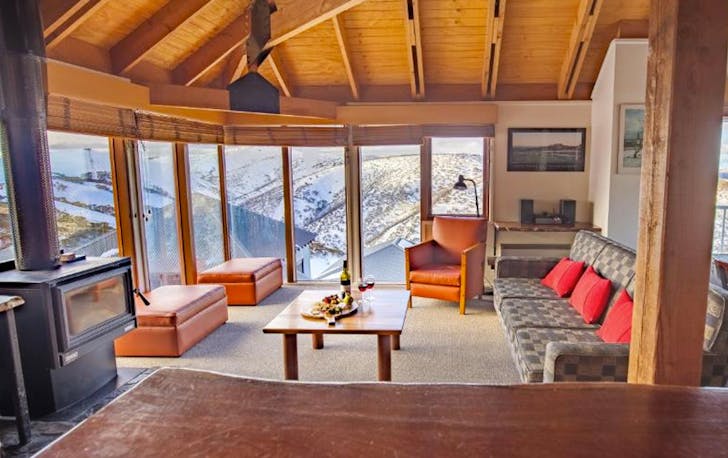 A large room with a fireplace and couches and windows, a best mt hotham accommodation. 