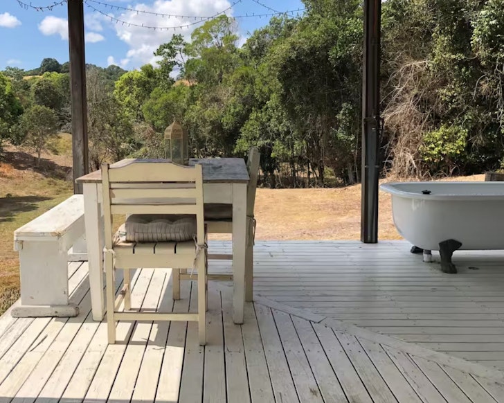 A view of the outdoor bath on the deck and the table at Noosa Hinterland Cabin Sunshine Coast