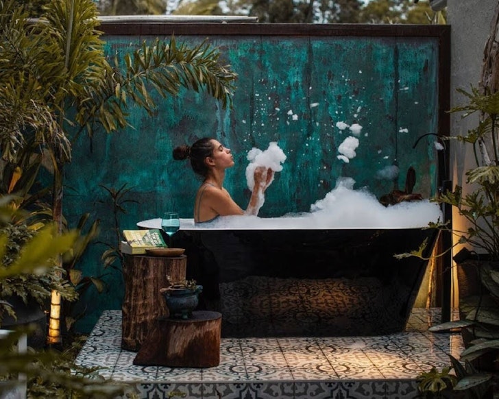 A woman blows bubbles in the outdoor bath at Sparkling Pool Oasis Airbnb near Brisbane Queensland