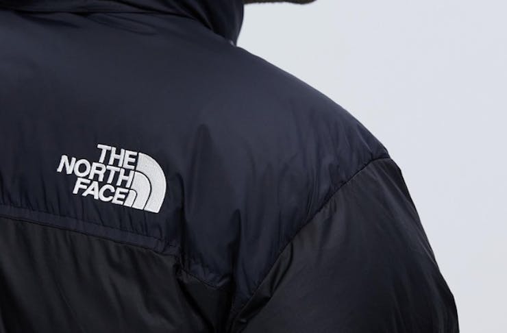 A persons shoulder with the North Face logo on a black jacket, one of the best mens puffer jacket. 