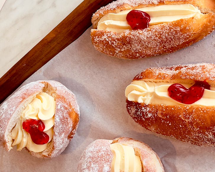 A close up of some old school sugar-dusted, cream-filled jam doughnuts. 