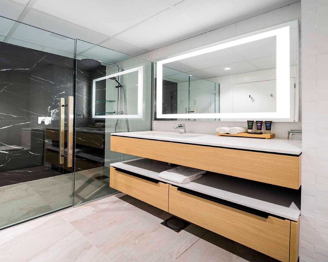 A sleek bathroom set up with massive, glass shower at Novotel Tainui Hamilton, one of the best hotels in Hamilton. 