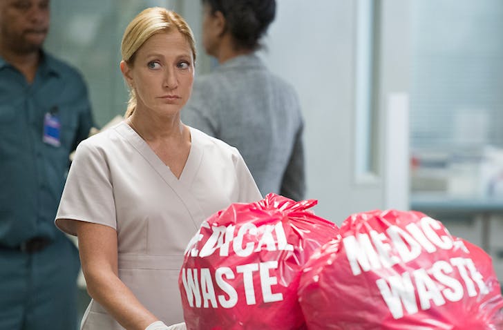 Edie Falco as Nurse Jackie looking suspicious as she disposes medical waste
