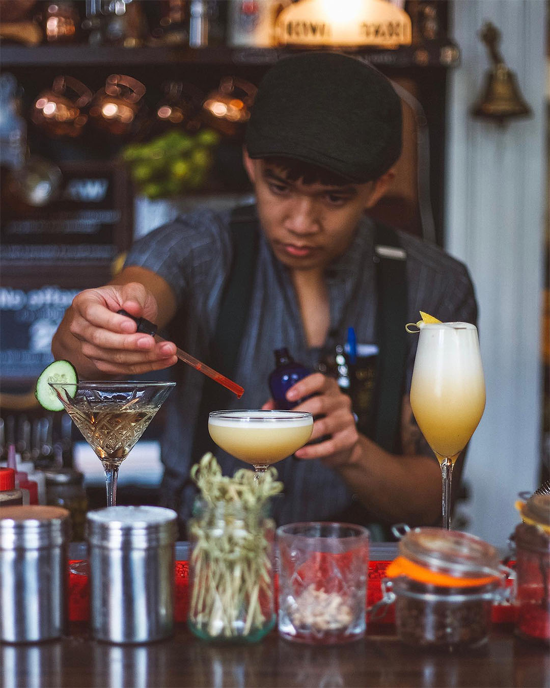 A flat-cap wearing bartender carefully prepares a drink at OGB, one of the best bars in Christchurch.