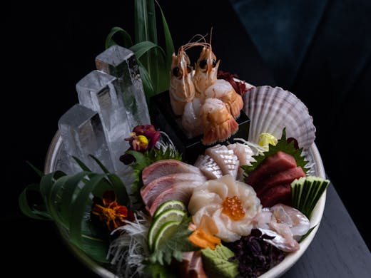 A bowl of sashimi decorated with edible flowers and ice