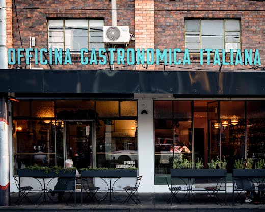 The exterior to a shopfront with people dining. 