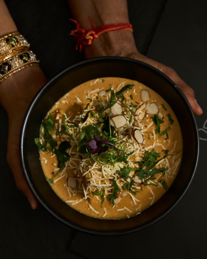 A person holds a bowl of chicken shah jahan from Oh Calcutta. 