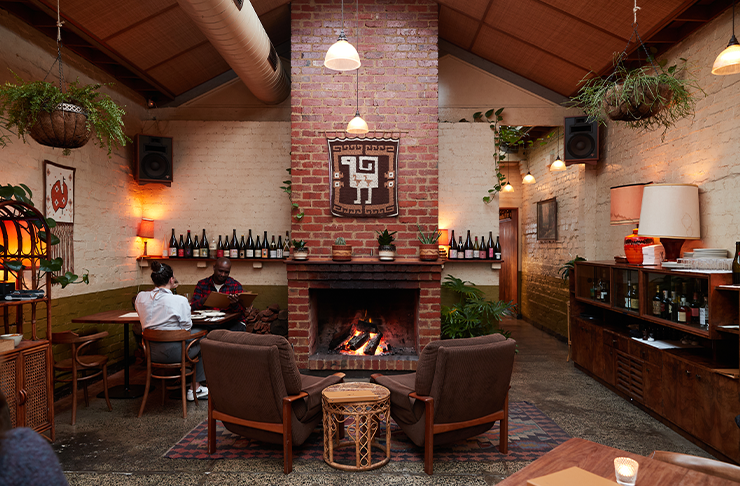 A fireplace sits in the middle of the space in one of the best bars in melbourne called Old Palm Liquor
