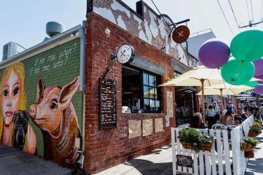 The exterior to Old Garage Cafe, a brick building with tables out-front and a window for take-away coffee.