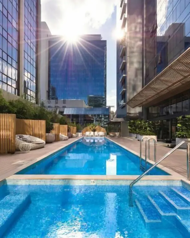 An outdoor pool framed by sky-scrapper buildings at One Global Resorts Parramatta.