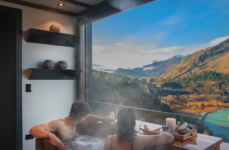 Two people look over the scenery at Onsen Hot Pools in Queenstown.