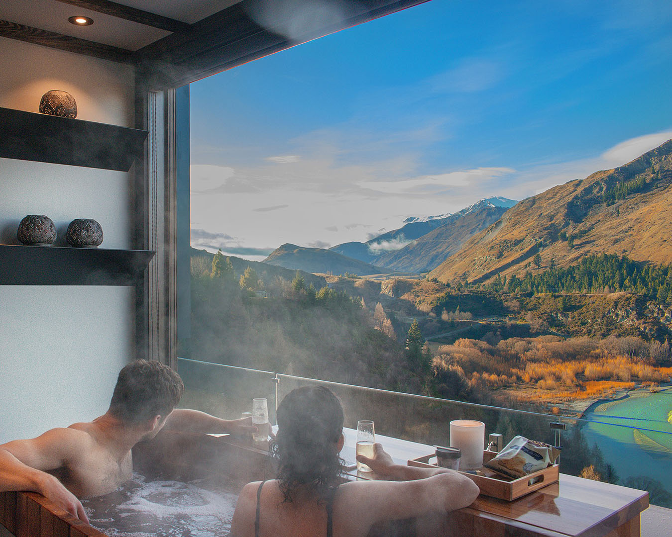 Two people look over the scenery at Onsen Hot Pools in Queenstown.