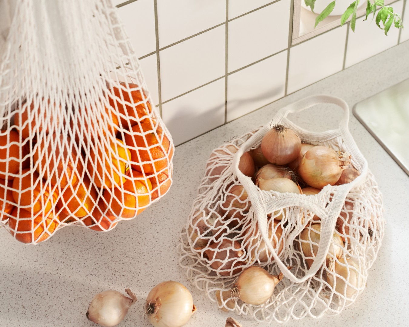 Oranges in IKEA net bags in a kitchen.