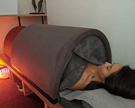 The infrared sauna bed with a woman lying inside it.
