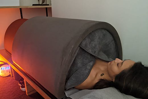 The infrared sauna bed with a woman lying inside it.