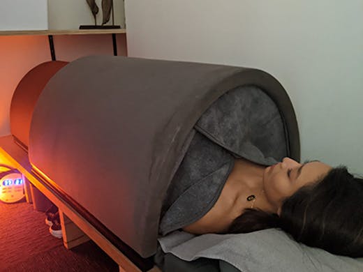The infrared sauna bed with a woman lying inside it.