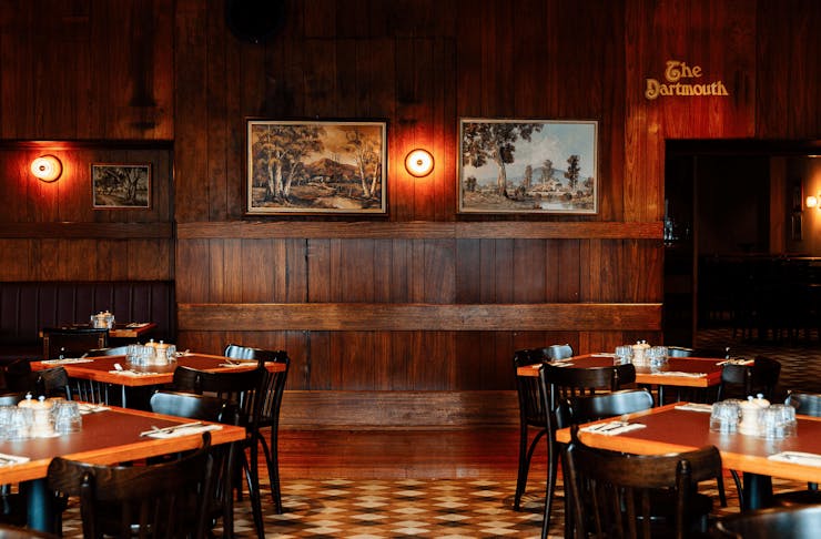 A dining room with wooden panelled walls and old-style artwork.