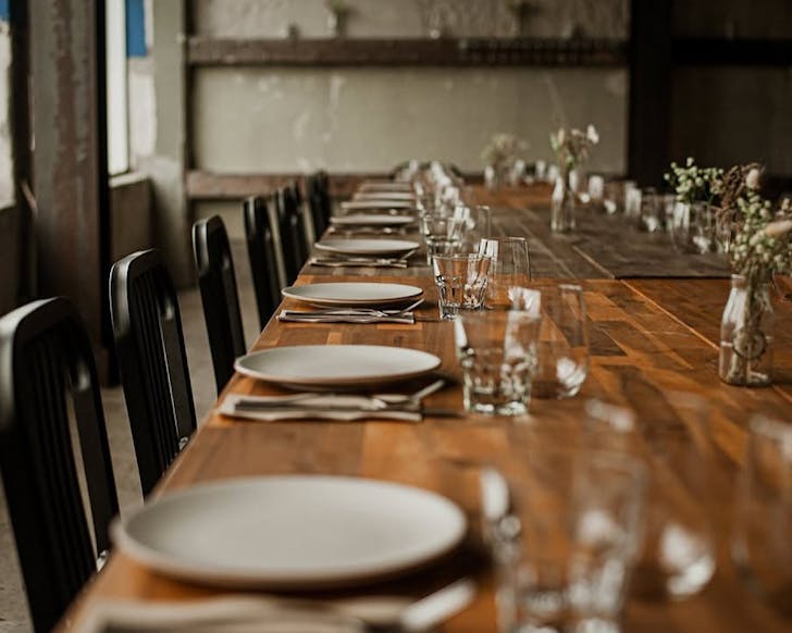 A long wooden table with black chairs and a sleek, minimalist aesthetic. 