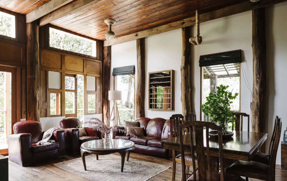 The lounge of a large wooden cabin with a long couch at one of the best romantic getaways in Victoria