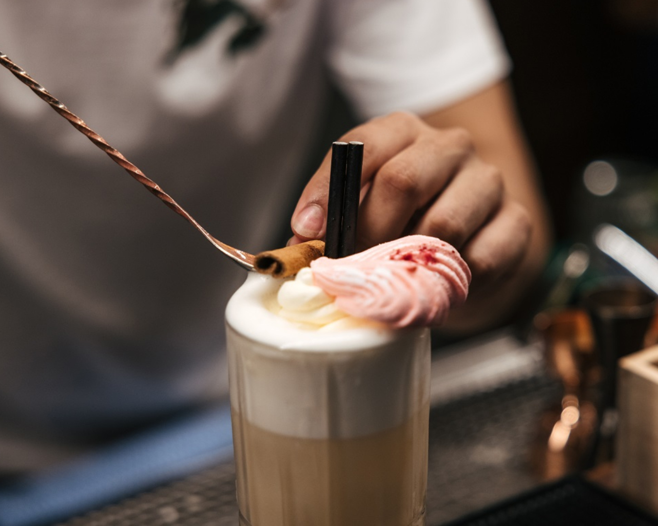 A bartender places a cinnamon quill atop a delicious Easter themed cocktail. 