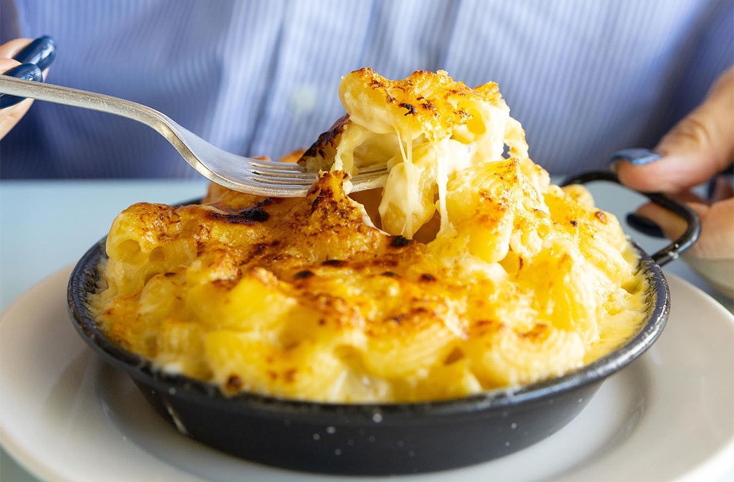 A person tucks into the legendary Mac N Cheese at The Oyster Inn on Waiheke Island.