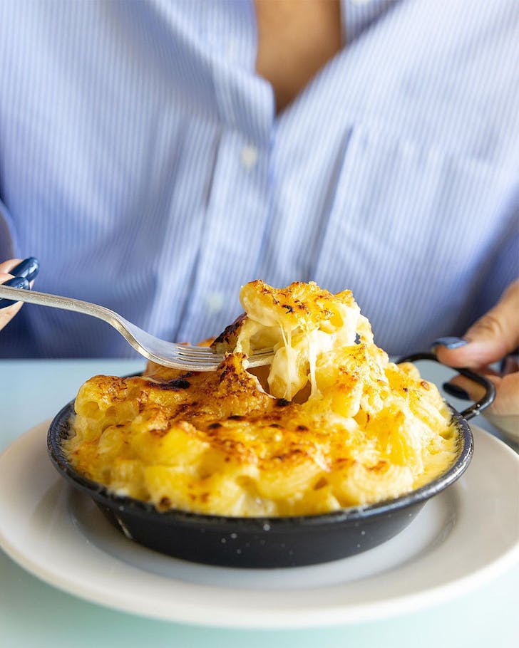 A person tucks into the legendary Mac N Cheese at The Oyster Inn on Waiheke Island.