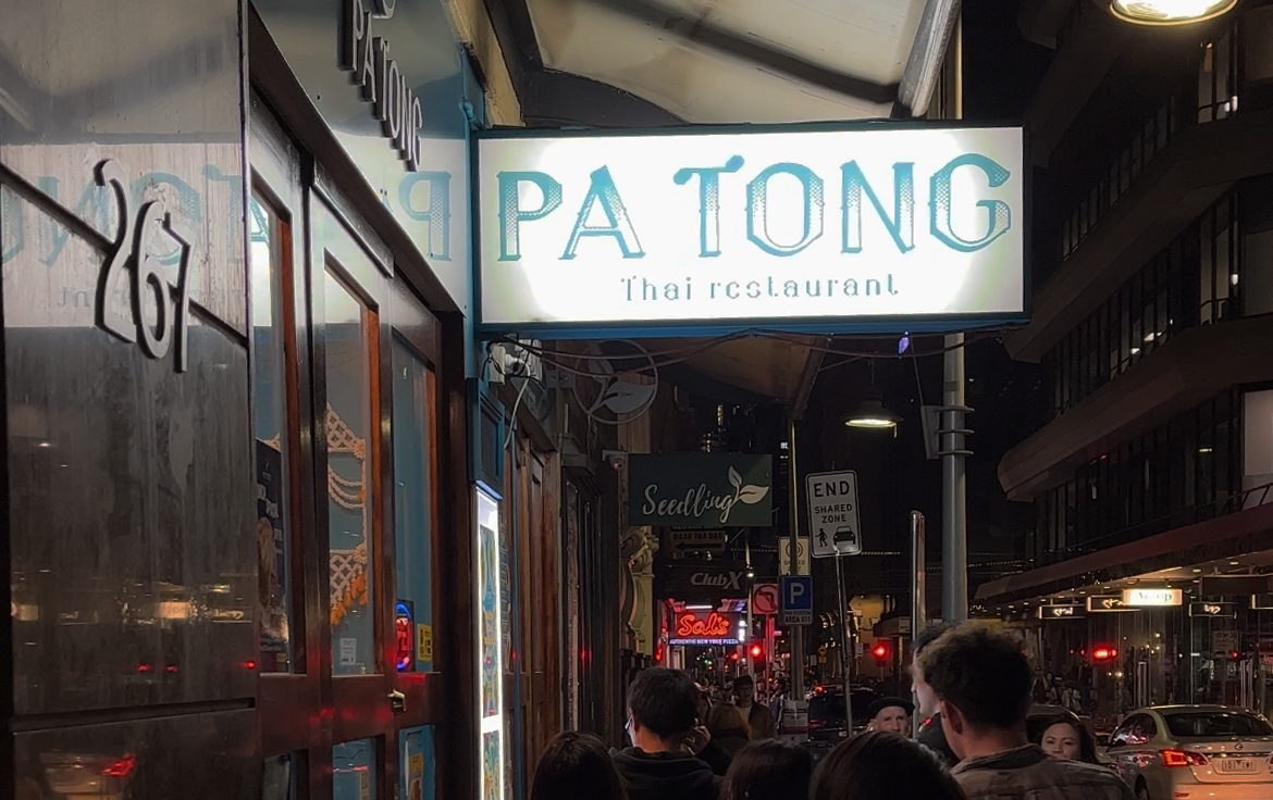 A restaurant sign with people walking in the city, a best thai restaurant Melbourne.
