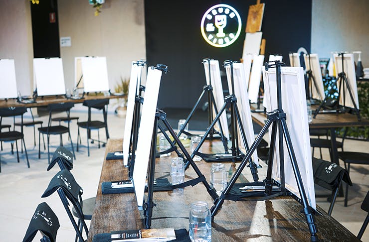 The inside of the paint studio with canvas on easels and plenty of chairs. 