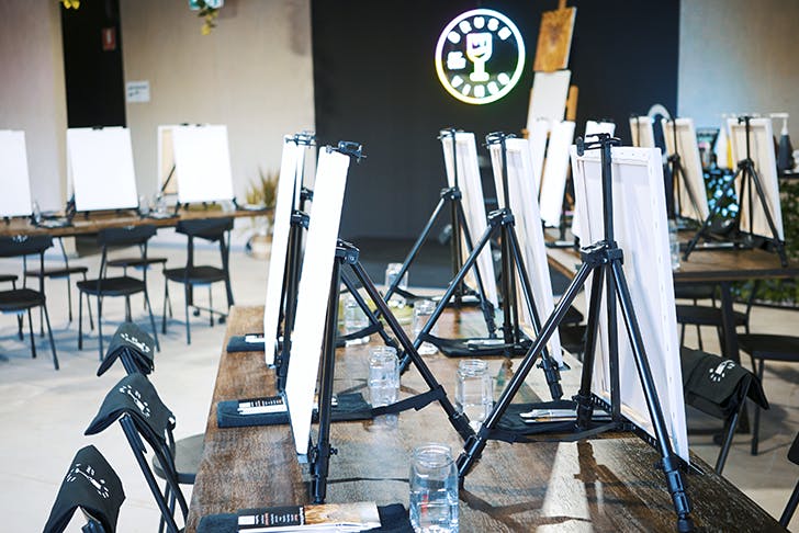 The inside of the paint studio with canvas on easels and plenty of chairs. 