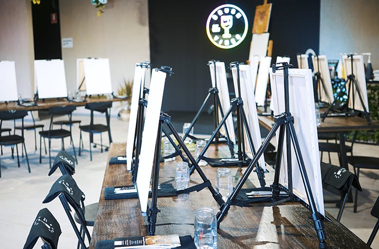 The inside of the paint studio with canvas on easels and plenty of chairs. 