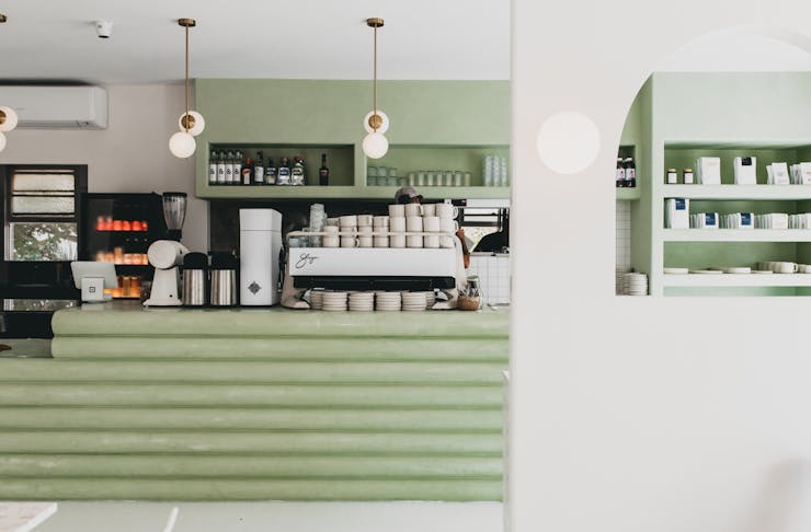 An interior shot of the mint green coffee counter and hanging lights with exposed bulbs at Palm Springs Burleigh.